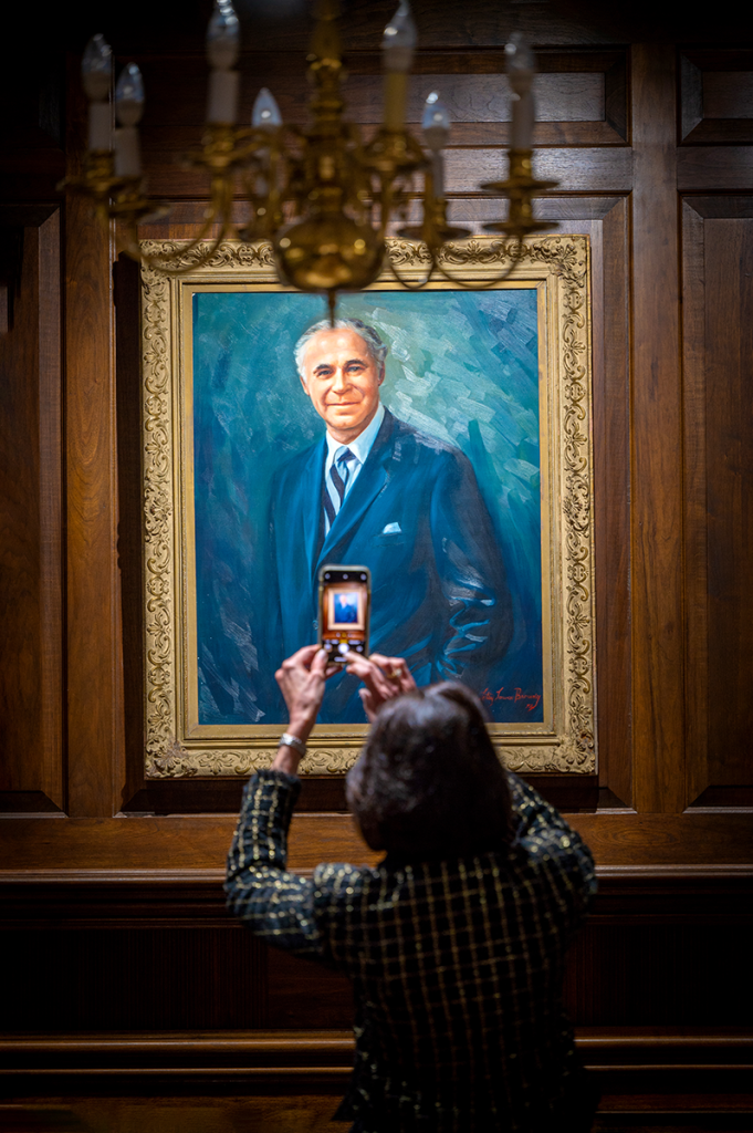 A woman takes a picture of a painting portrait with her phone