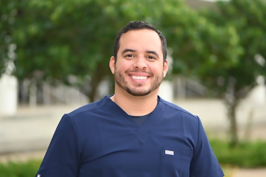 man smiling outside with trees in the background