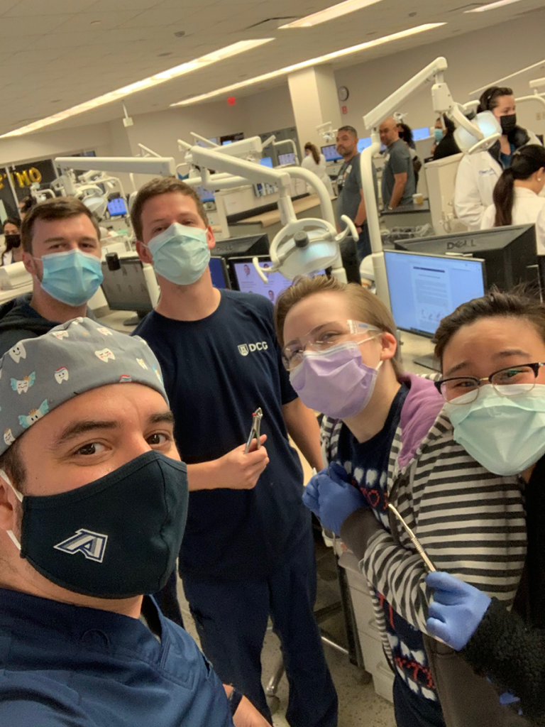 four dentists wearing masks in an exam room