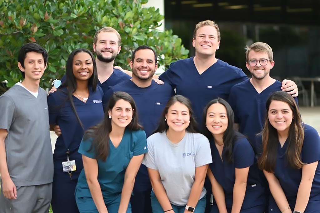 large group of students pose and smile for a photo outside