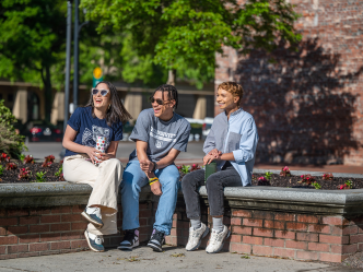 Three students sitting and smiling in Downtown Augusta.