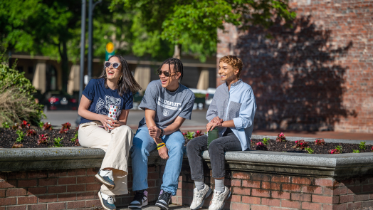 Three students sitting and smiling in Downtown Augusta.