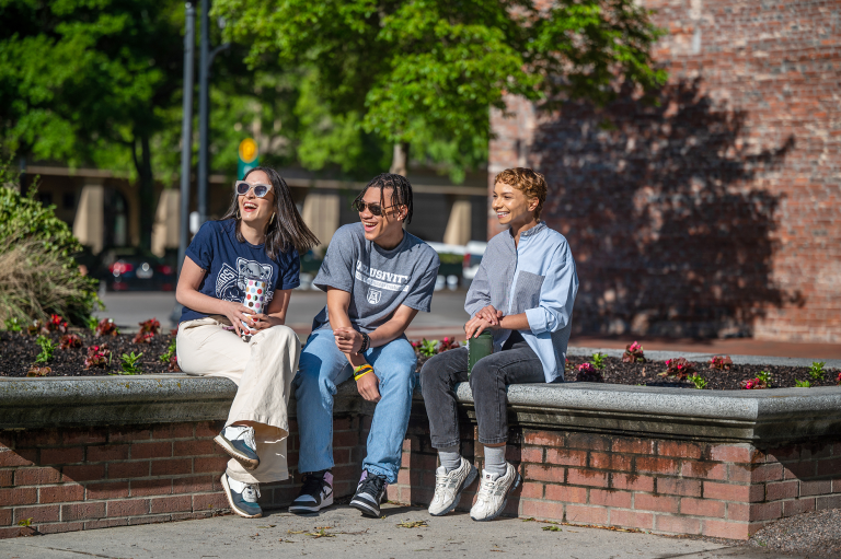Three students sitting and smiling in Downtown Augusta.