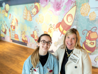 Two women smiling in front of art work
