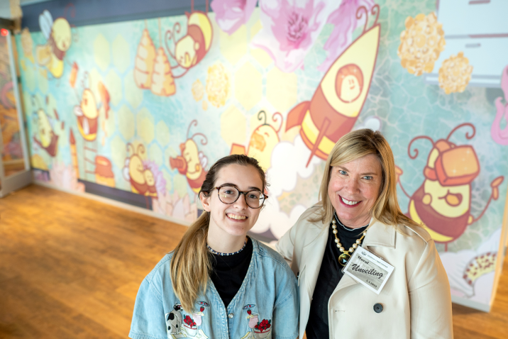 Two women smiling in front of art work
