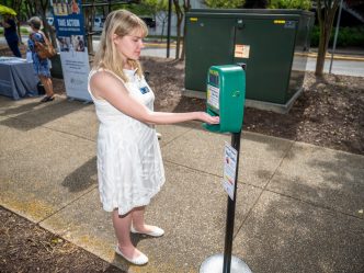 Female receiving sunscreen from automatic dispenser