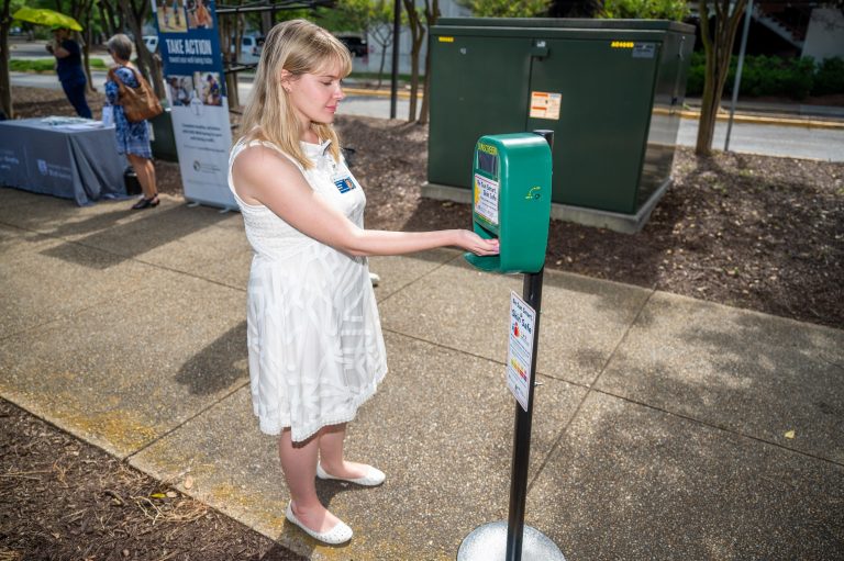 Female receiving sunscreen from automatic dispenser