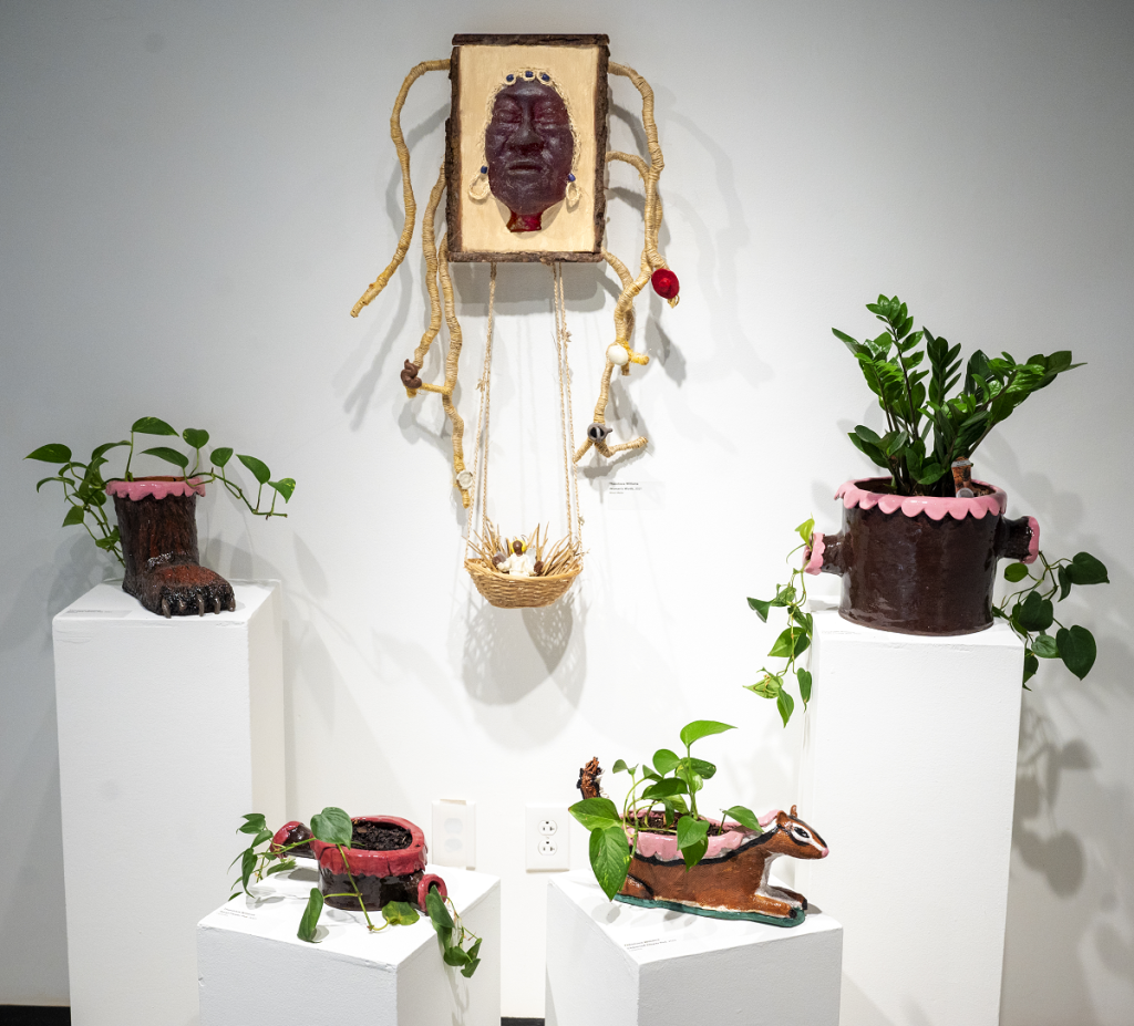 Art exhibit featuring clay sculptures with flowers in them