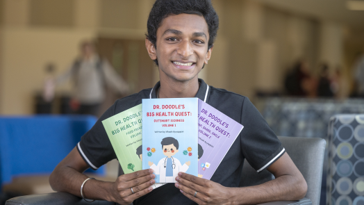 Student holds three books he wrote