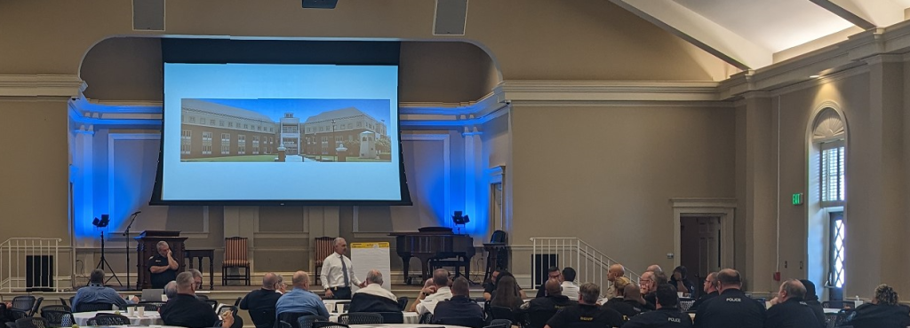 A wide shot of a meeting in a church with a photo on a screen