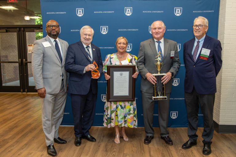 People smiling and holding awards