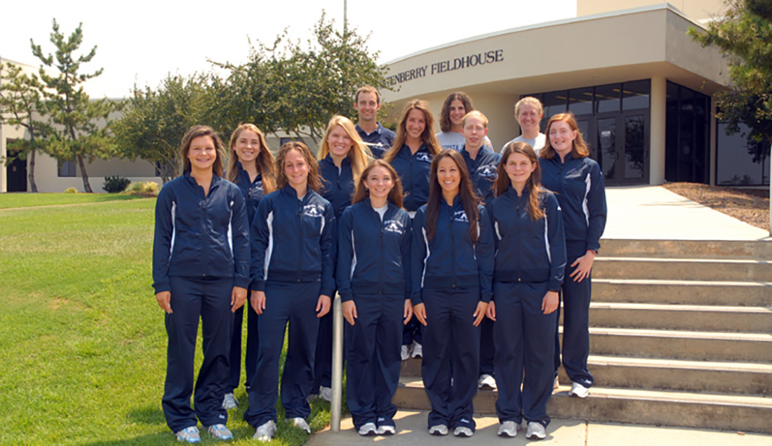 Women posing for team photo with male coach