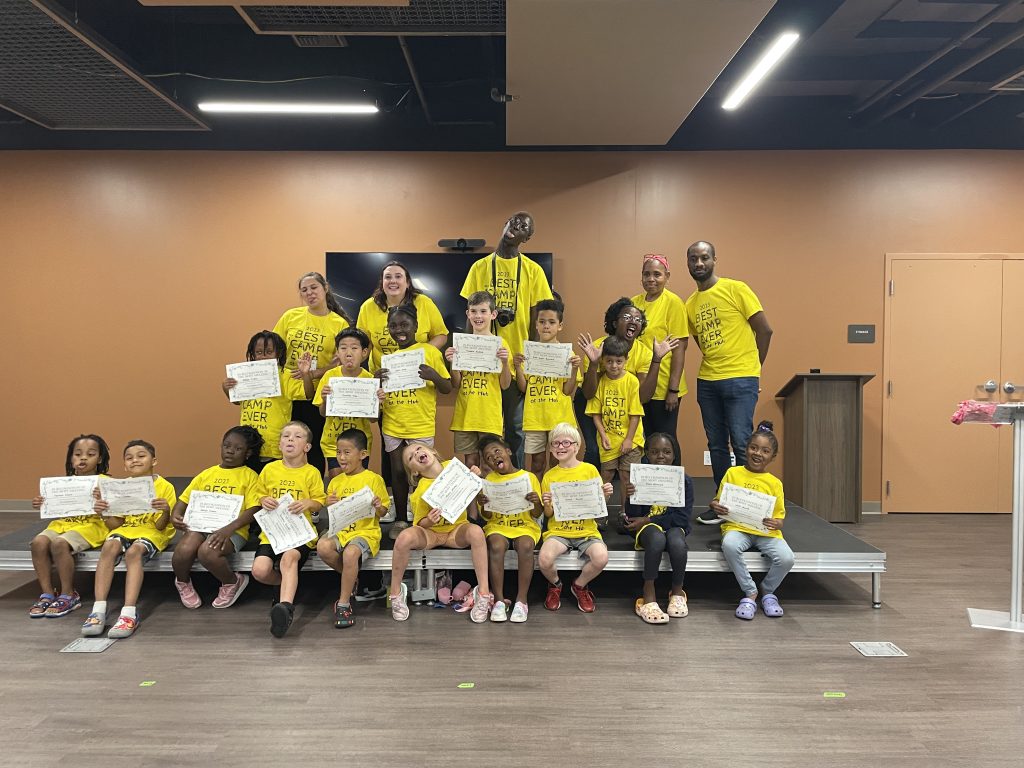 students and their instructors pose on a stage