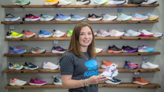 Woman holding a running shoe in front of more shoes