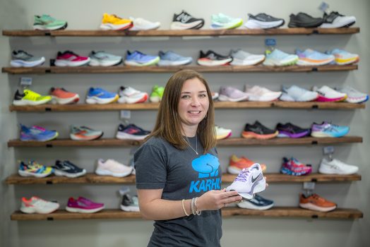 Woman holding a running shoe in front of more shoes
