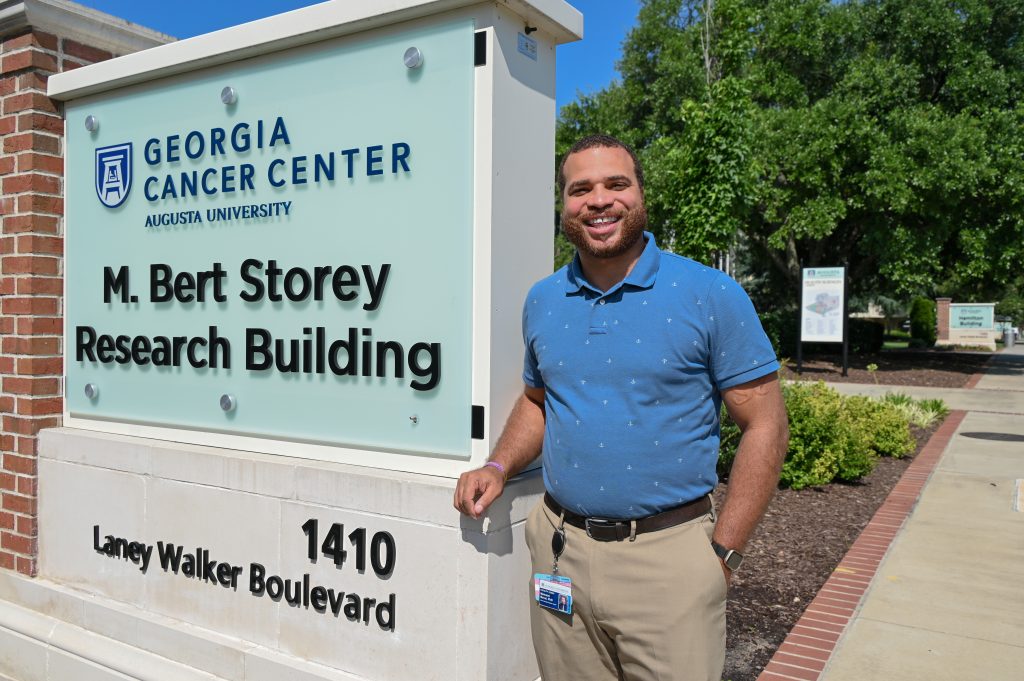 Man in a polo shirt stands beside the M. Bert Storey Research Building sign.