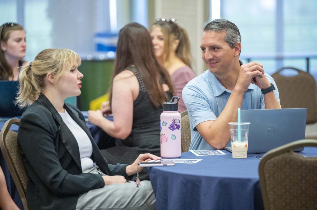 Man and a woman talking at the annual Summer Summit.