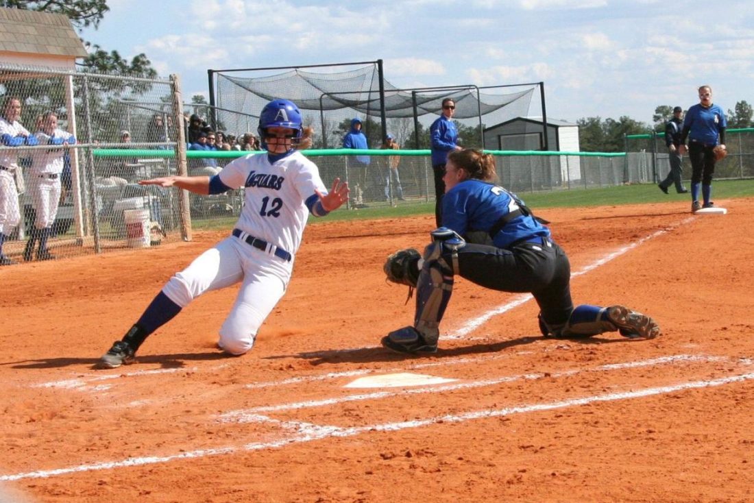 Woman sliding into home while avoiding a tag from catcher