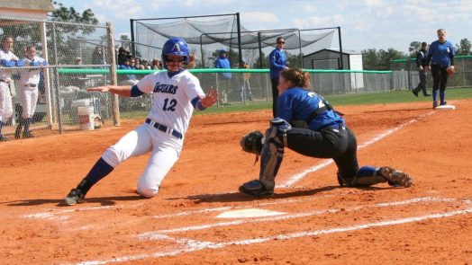 Woman sliding into home while avoiding a tag from catcher