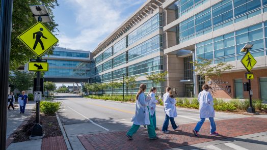 People in white coats walking across college campus