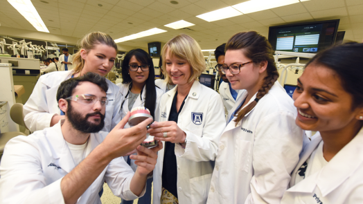 Dental students look at a model of a mouth