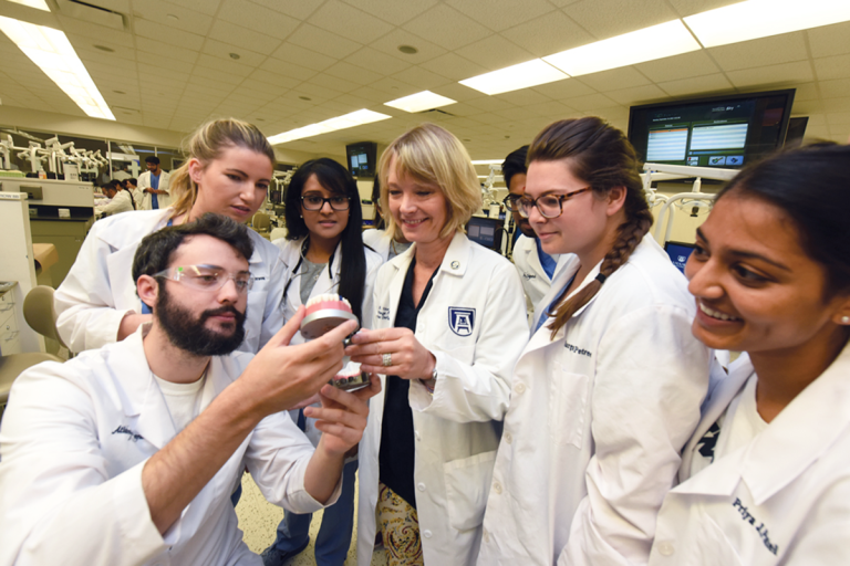 Dental students look at a model of a mouth