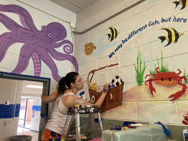 student painting a mural of an underwater landscape