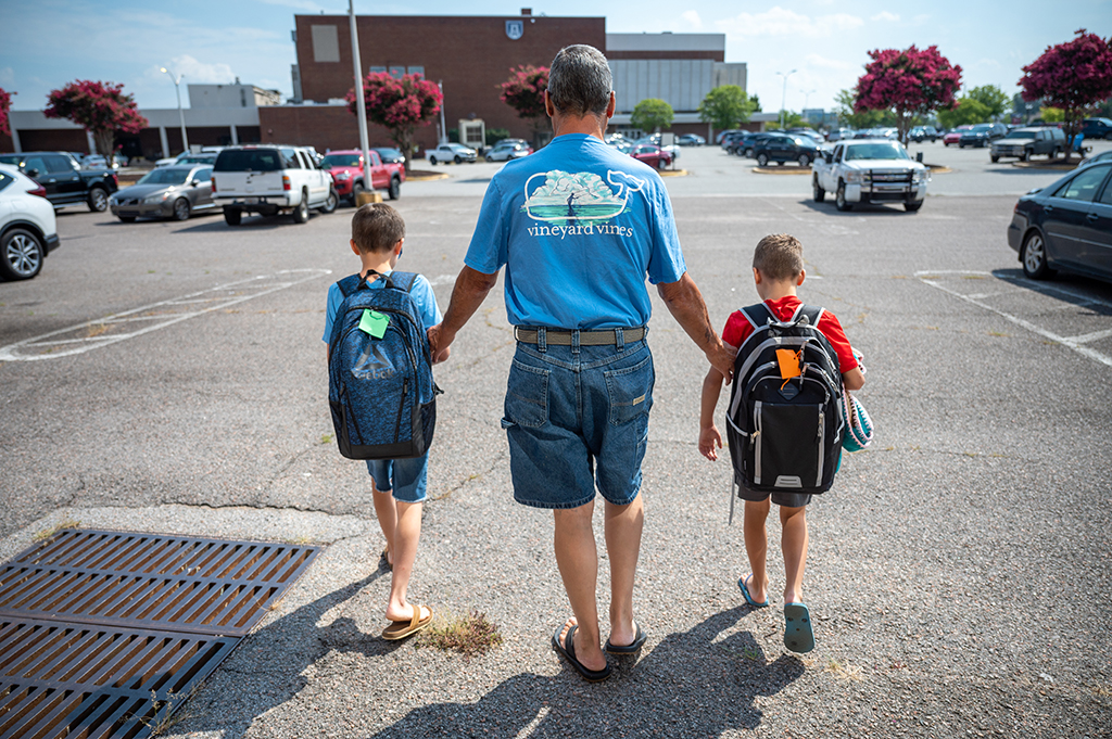 Adult walking with two kids wearing backpacks