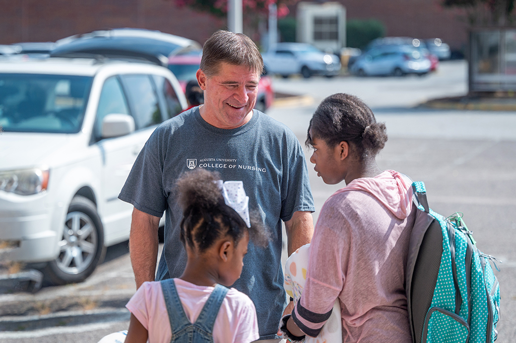 Man talking with kids holding new backpacks