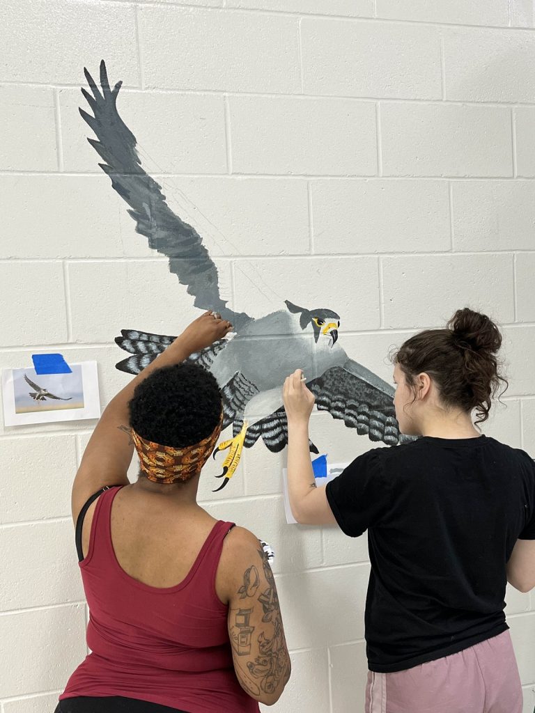 two students painting a falcon