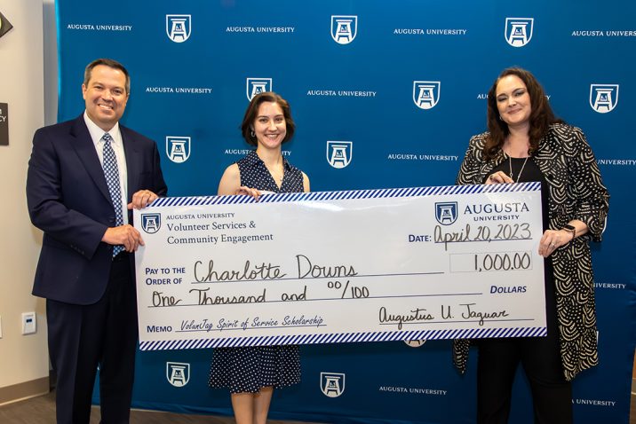 Man and woman present big check to another woman
