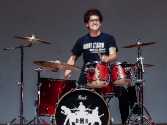 A man plays the drums on stage at a talent show