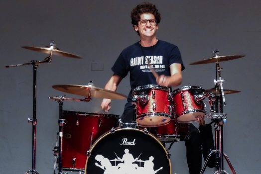 A man plays the drums on stage at a talent show