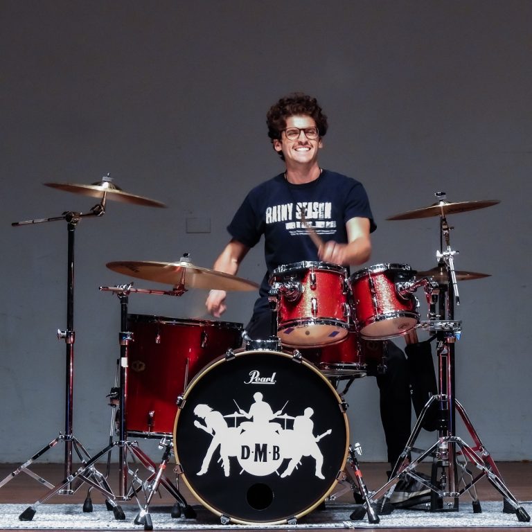 A man plays the drums on stage at a talent show