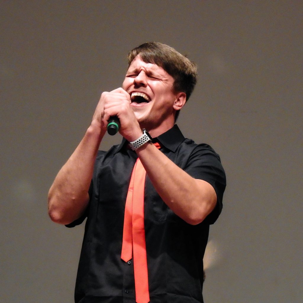 A man sings on stage during a talent show
