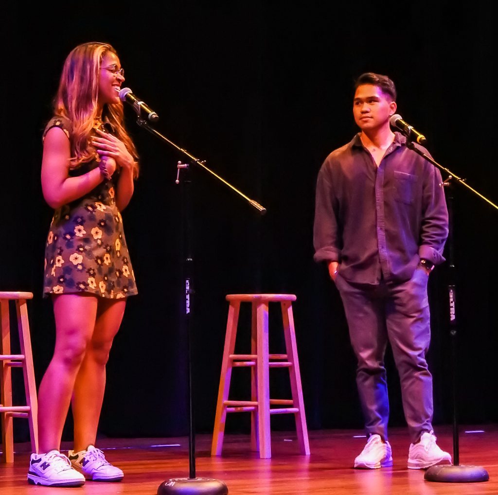 A young man and woman perform on stage at a talent show