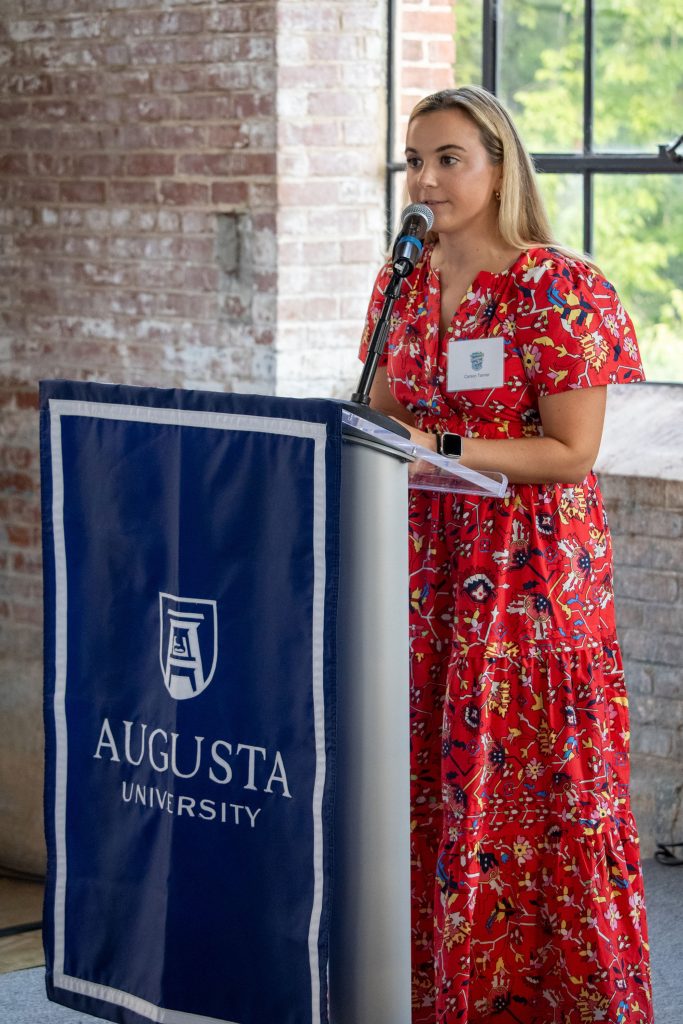 A woman stands at a podium while giving a presentation.