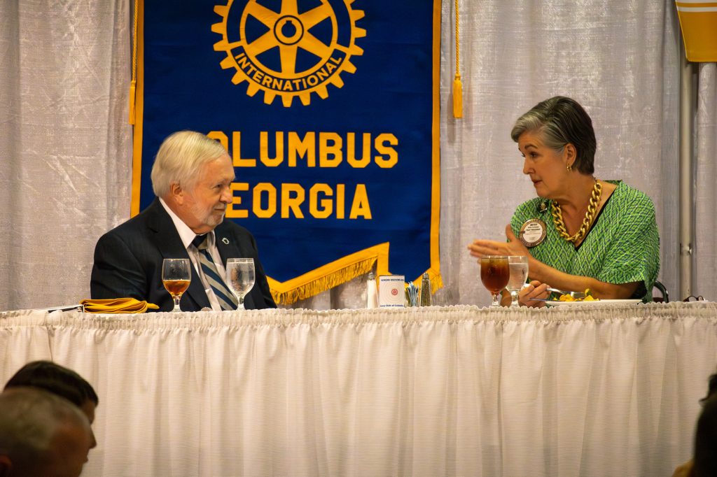 A man and a woman sit at a banquet table talking.