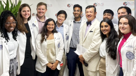 Doctor and medical students pose in front of a banner at a new clinic location