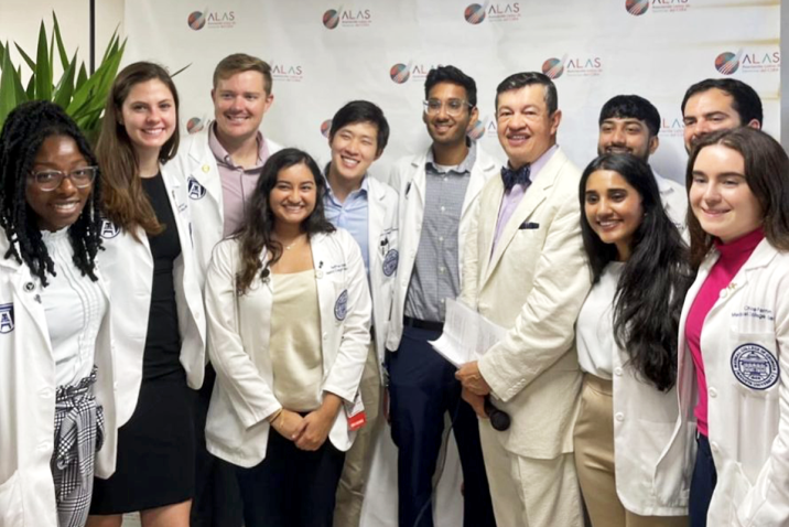 Doctor and medical students pose in front of a banner at a new clinic location