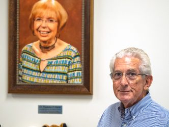 a man stands in front of a photo of his late wife, Dr. Paulette P. Harris, for whom the literacy center is now named