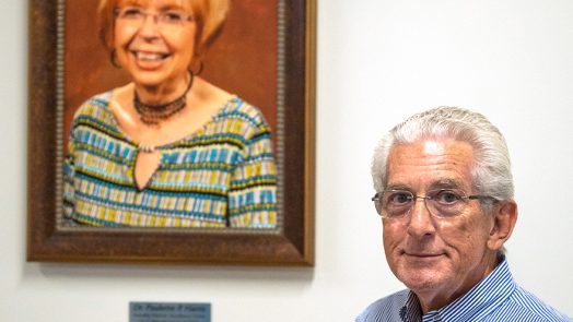 a man stands in front of a photo of his late wife, Dr. Paulette P. Harris, for whom the literacy center is now named