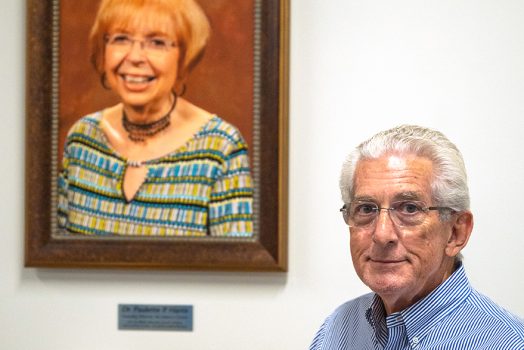 a man stands in front of a photo of his late wife, Dr. Paulette P. Harris, for whom the literacy center is now named