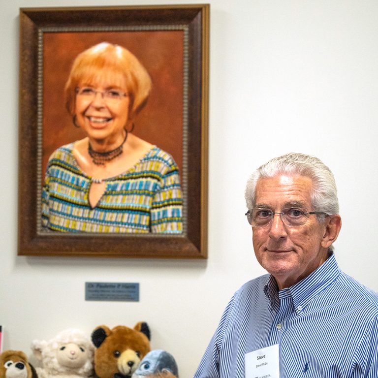 a man stands in front of a photo of his late wife, Dr. Paulette P. Harris, for whom the literacy center is now named