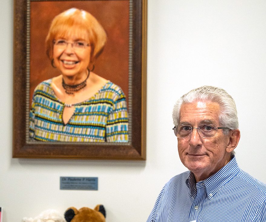 a man stands in front of a photo of his late wife, Dr. Paulette P. Harris, for whom the literacy center is now named