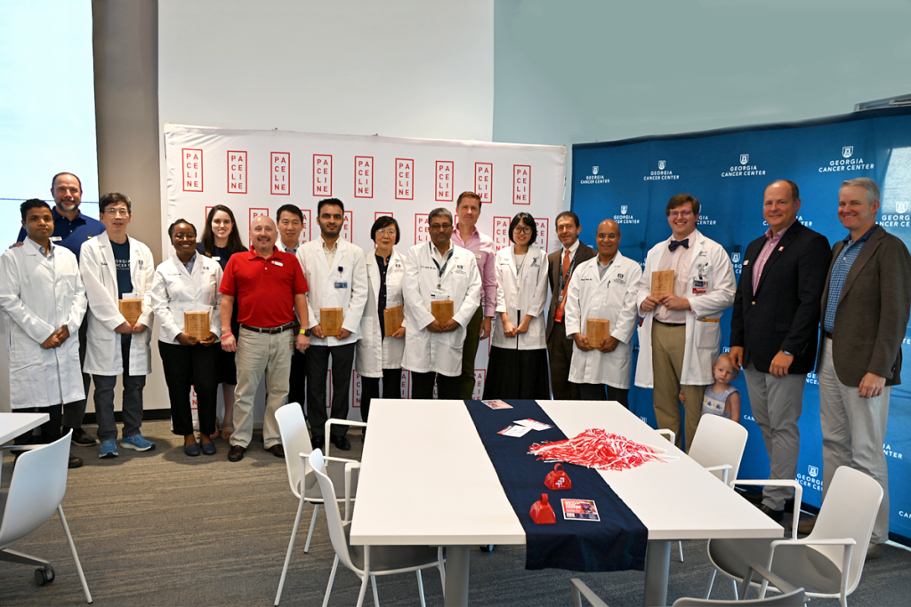 A group of people stand in front of a backdrop for an award ceremony.