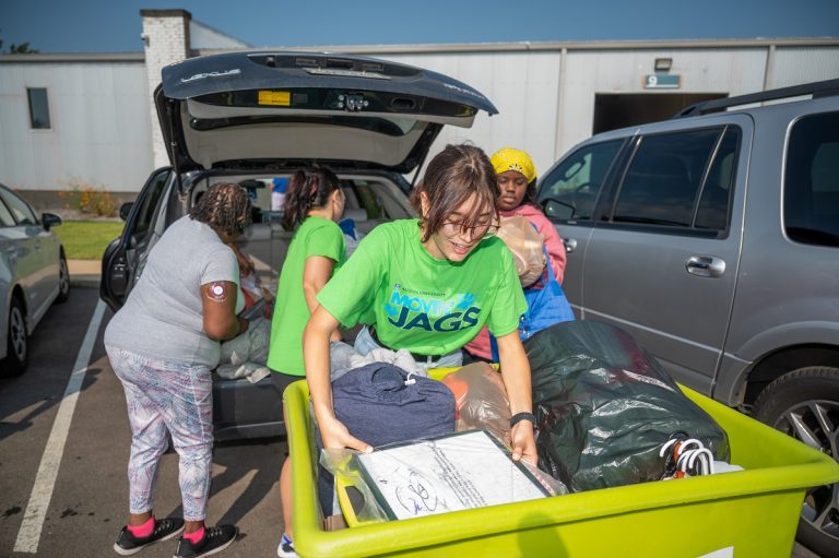 Students volunteering to help other students unload a car