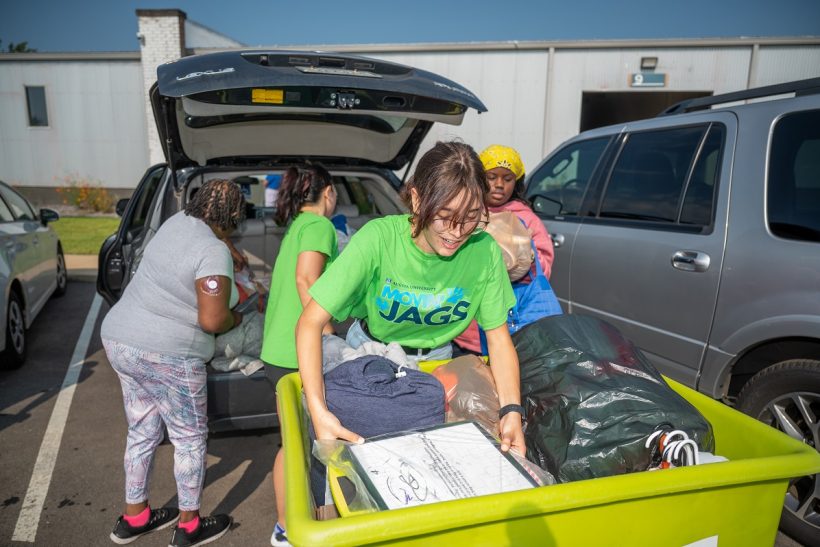 Students volunteering to help other students unload a car