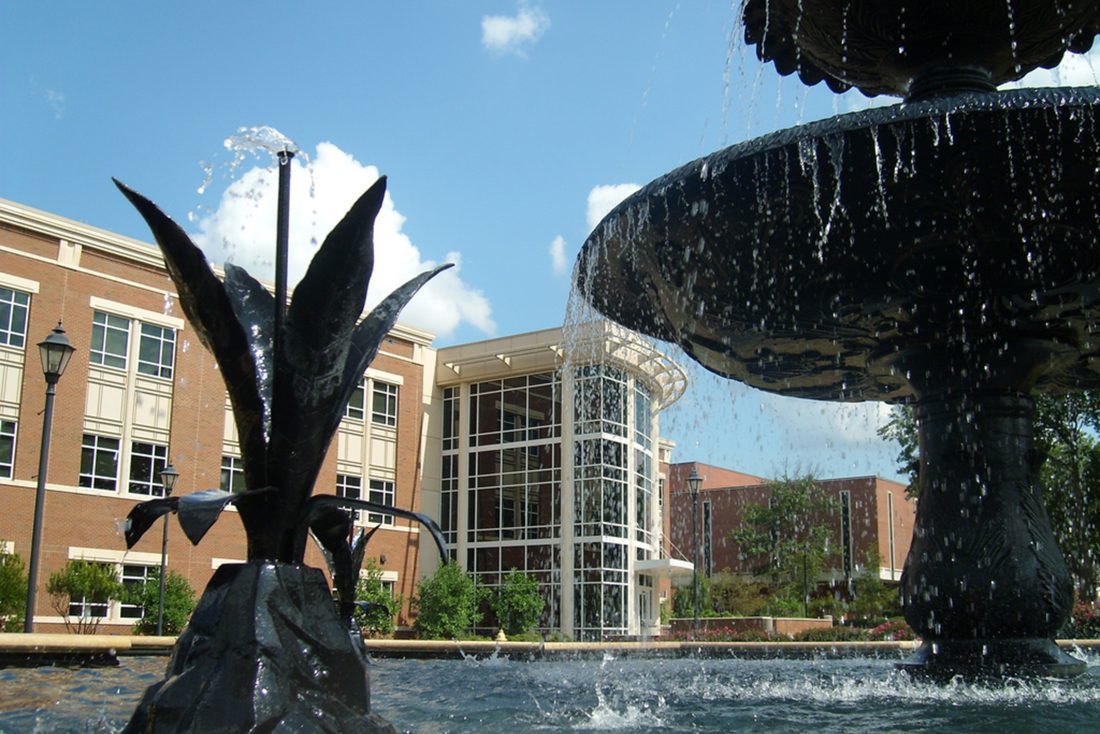 University Hall is seen in the background of a fountain on the Summerville Campus