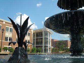 University Hall is seen in the background of a fountain on the Summerville Campus